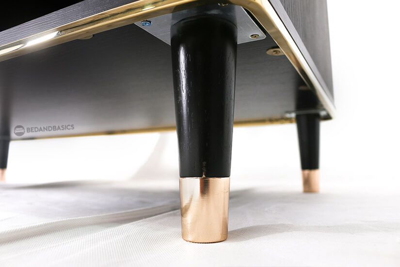 The stand is supported by four tapered wooden legs tipped with a bright rose-gold finish for a strong look.