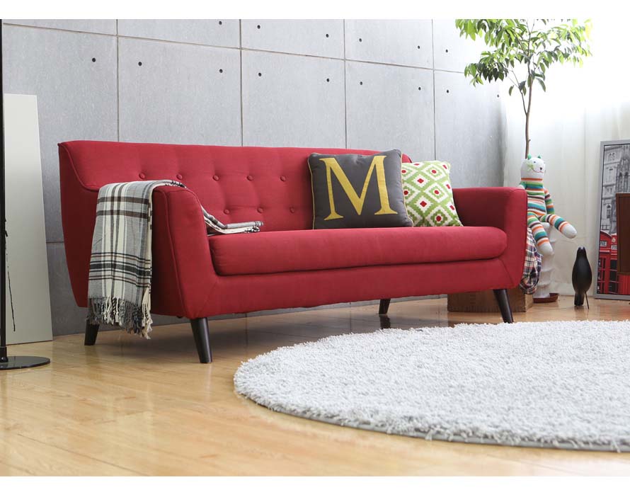 The Alba sofa red with cushions on it and a stylish scarf. The Sofa is seen in natural lighting.