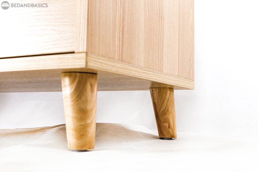 The stand is supported by four strong tapered wooden legs that showcases a beautiful wood swirl pattern.