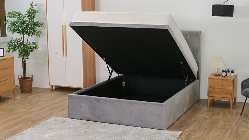 Closed wooden bed base wrapped in black woven fabric. 