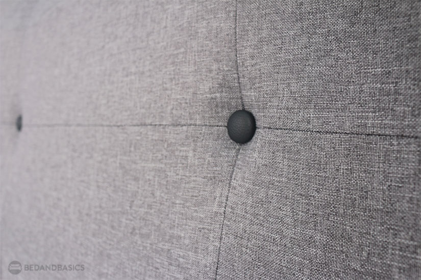 Classic black buttons pinned to the headboard for a grid-tufted look.